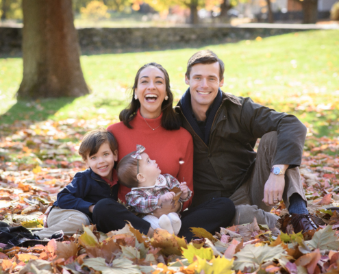 fall family portrait with baby and toddler with fall leaves and mom and dad smiling