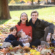 fall family portrait with baby and toddler with fall leaves and mom and dad smiling